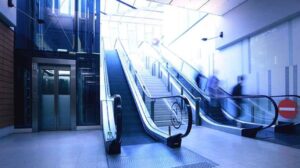 Photograph of an elevator next to a set of escalators with a stairway between them.